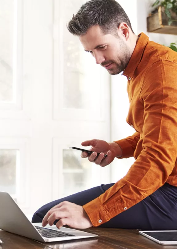Man using a laptop and smartphone