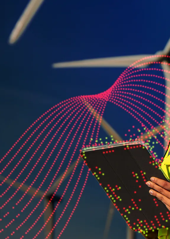 Woman stood in front of wind turbine dressed in a Hi-Vis and protective hard hat